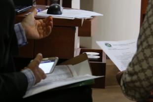 #PraCegoVer: Foto mostra detalhe da mão de um parlamentar segurando celular e documentos. Ao lado dele, outra pessoa segura um documento.