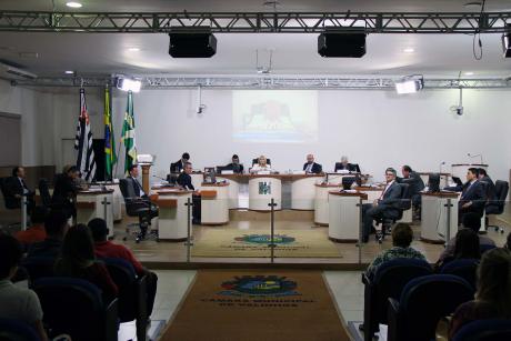 #PraCegoVer: Foto mostra o plenário da Câmara com os vereadores no centro e parte do público presente nas laterais.
