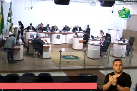 #PraCegoVer: Foto mostra imagem capturada pela TV Câmara. Nela está o plenário, com os vereadores sentados em seus lugares, e no canto inferior direito está o intérprete de Libras, fazendo a tradução em tempo real.