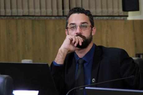 #PraCegoVer: Foto mostra o vereador Alécio Cau (PDT) sentado em seu lugar no plenário, prestando atenção na sessão ordinária.