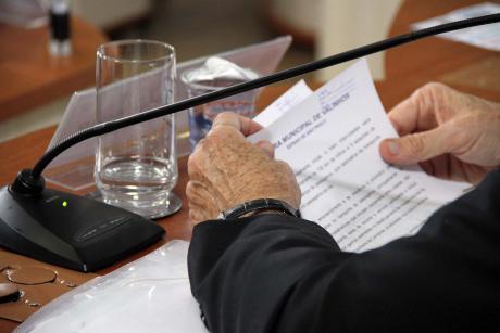 #PraCegoVer: Foto mostra braços de um vereador na mesa. Nas mãos, ele folheia documentos.