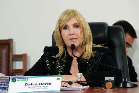 #PraCegoVer: Foto mostra a vereadora Dalva Berto sentada em seu lugar, na cadeira de presidente da Câmara, discursando para o público presente.