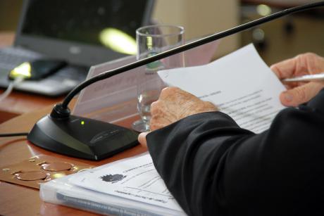 #PraCegoVer: Foto mostra mão de um vereador, em cima de sua mesa, no plenário da Câmara, segurando documentos.