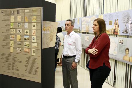 #PraCegoVer: Foto mostra dois visitantes da exposição, observando painéis que contam histórias relacionadas a Dom João VI.