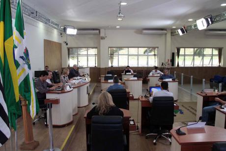 #PraCegoVer: Foto mostra o plenário da Câmara visto de lado, com os vereadores sentados em seus lugares. No canto esquerdo estão as bandeiras do município, do estado e do Brasil.