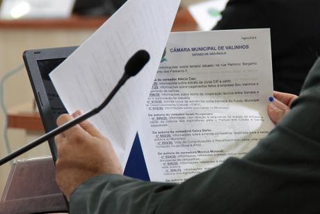#PraCegoVer: Foto mostra vereador lendo documento durante a sessão ordinária. A fotografia está focando apenas nos braços, mãos e no documento.