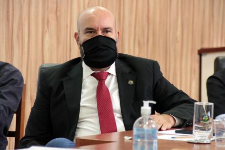 #PraCegoVer: Vereador César Rocha olha para frente sentado à sua tribuna da mesa diretora. Ele veste uma máscara preta. 