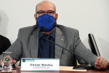 #PraCegoVer: Vereador César Rocha acompanha a sessão sentado à sua tribuna na mesa diretora. Ele olha para frente e usa uma máscara. 