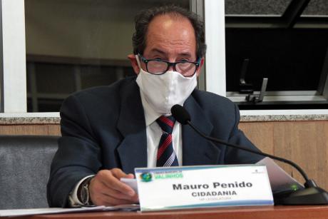 #PraCegoVer: Vereador Mauro Penido fala ao microfone da sua tribuna na Câmara durante a sessão. Ele usa uma máscara e segura um papel.