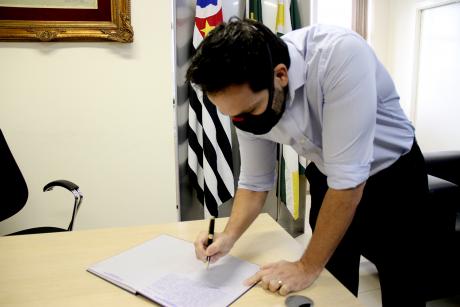 #PraCegoVer: Foto mostra o vereador Dr. André assinando o livro de posse.
