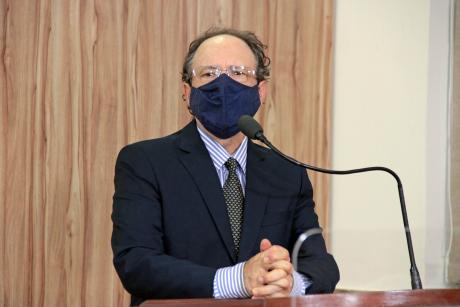 #PraCegoVer: Henrique Conti discursa ao microfone na tribuna da Câmara. Ele usa máscara e cruza os dedos enquanto fala. 