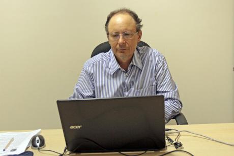 #PraCegoVer: Vereador Henrique Conti acompanha a sessão a partir de um computador portátil em uma mesa