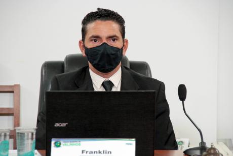 #PraCegoVer: Franklin olha para frente em seu assento na mesa diretora da Câmara. Ele usa máscara.