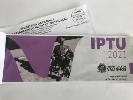 #PraCegoVer: Carnê do IPTU 2021 de Valinhos. As folhas têm a foto da estátua de Adoniran Barbosa na capa, com grafismos em cor vibrante. No carnê está escrito: "IPTU 2021 - Prefeitura de Valinhos - Imposto Predial e Territorial Urbano". 