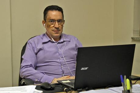 #PraCegoVer: Foto mostra o vereador Fábio Damasceno em seu gabinete. Ele posa para foto, em frente ao seu notebook, de onde participa da sessão ordinária virtual.