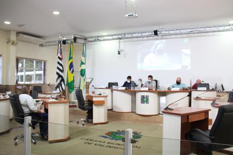 #PraCegoVer: Foto mostra os vereadores Gabriel Bueno, Rodrigo Toloi e César Rocha sentados na mesa principal do plenário, ouvindo a ex-diretora Ana Maria Desti Júlio.