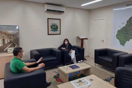 #PraCegoVer: Foto mostra o presidente da Câmara conversando com a presidente da Feav, Eliane Macari. Ambos estão sentados em poltronas pretas, no Gabinete da Presidência.