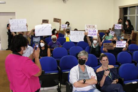 #PraCegoVer: Foto mostra manifestantes na Câmara erguendo cartazes que dizem "Salve a lagoa", Sanciona, prefeita" e "Não ao aterramento da lagoa".