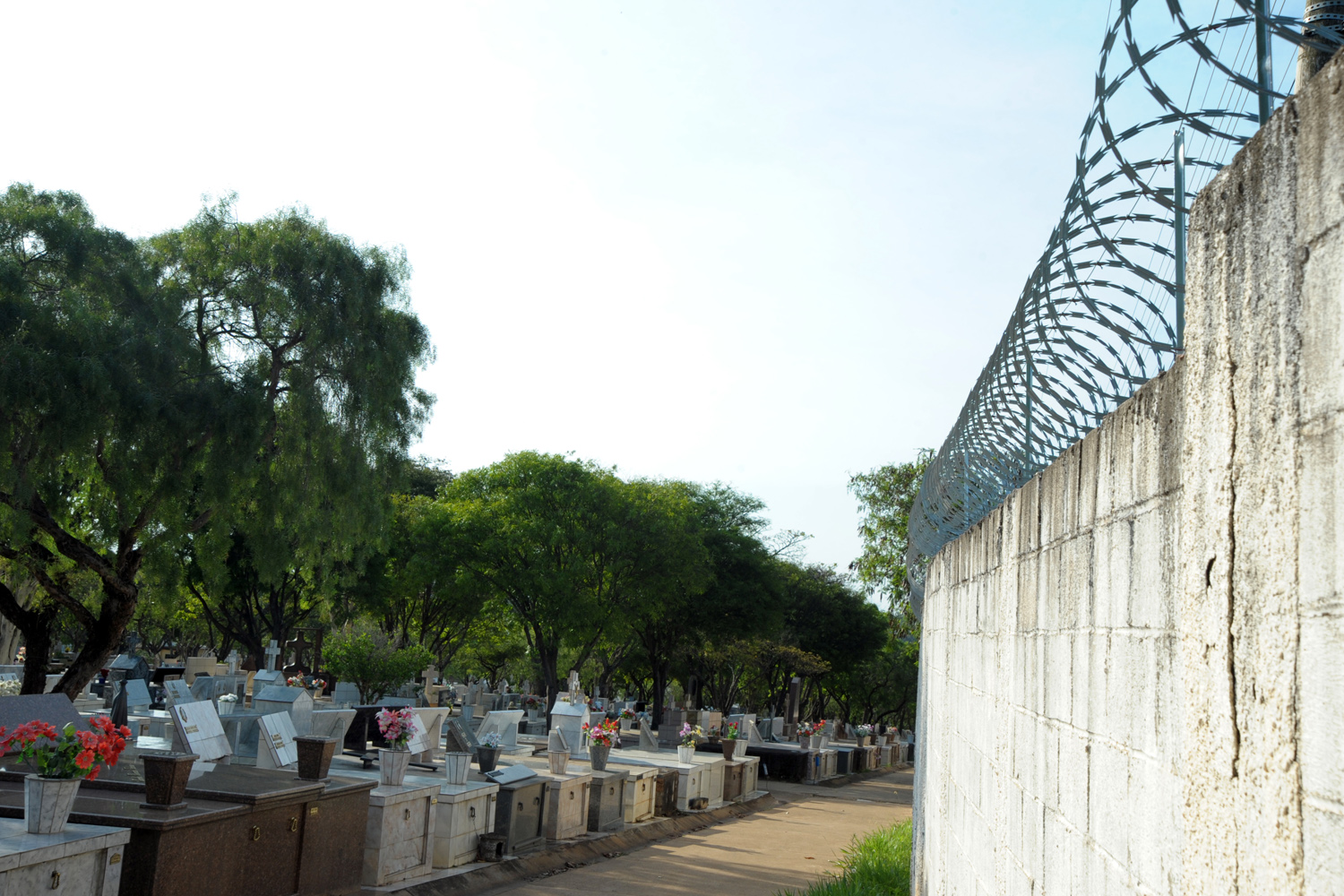 #PraCegoVer: Foto mostra muro e túmulos do cemitério São João Batista.