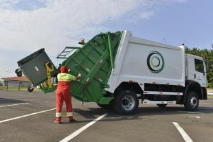 #PraCegoVer: Foto mostra caminhão de lixo sendo operado por funcionário que faz a limpeza urbana.